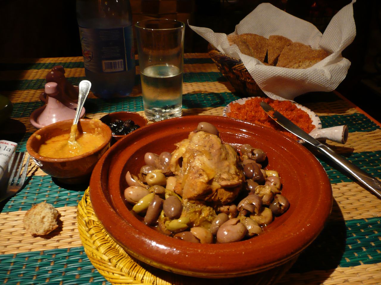 Restaurant table set with Moroccan chicken tagging, bread, and a glass of water